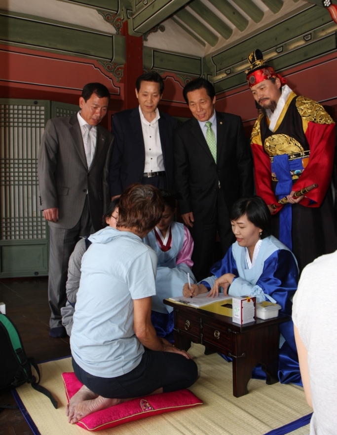 한 외국인이 수원 화성행궁 한방 무료 진료 및 한의약 체험 행사에서 정조대왕이 지켜보는 가운데 설명을 듣고 있다.