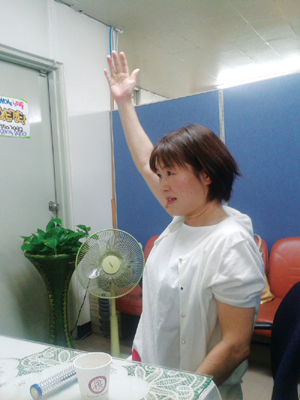 오십견 통증을 호소한 야마시타씨가 서금요법 치방을 받고 오른쪽 어깨를 들어 올리고 있다.